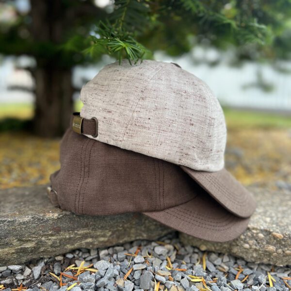 Two hats are sitting on a rock near a tree.